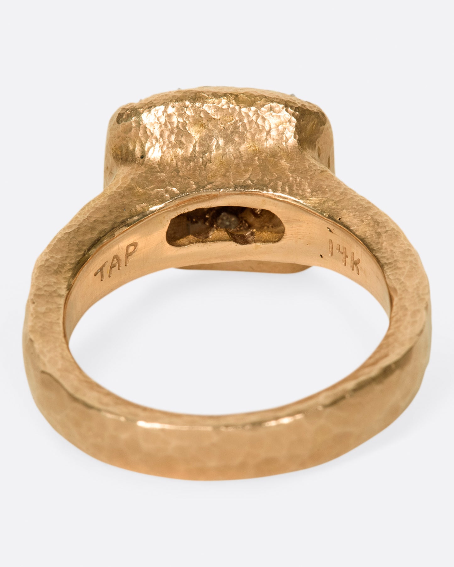 A hammered, hefty rose gold ring with inverted diamonds scattered across its rectangular face.