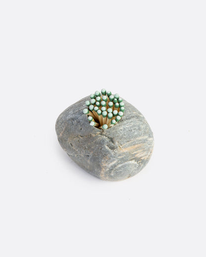A light grey stone match striker with matches in a hole on the top. Shown from the top.