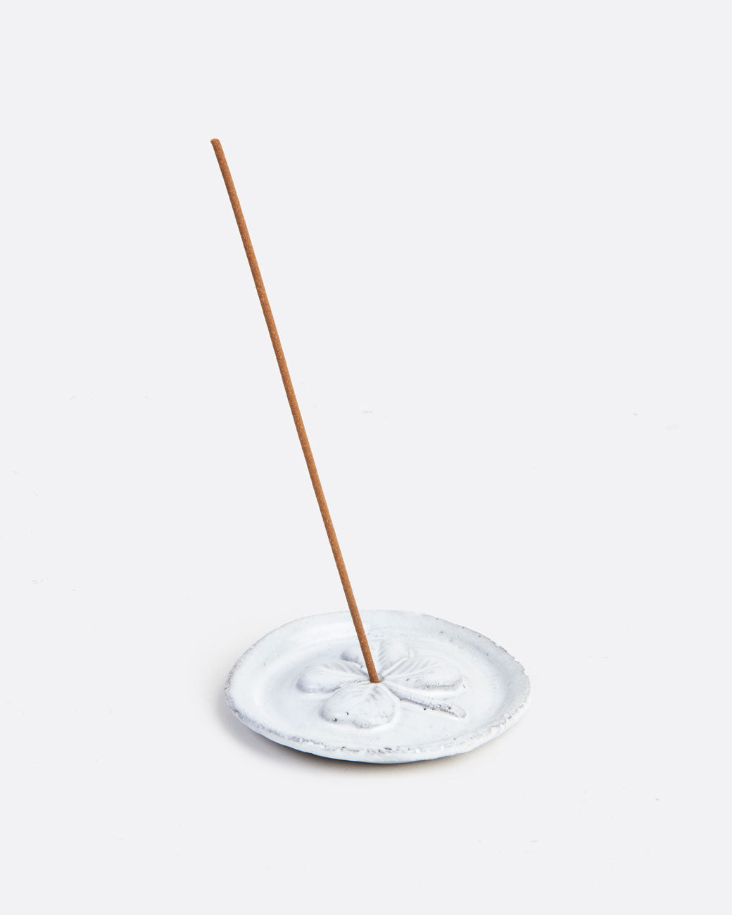 white incense holder with an incense stick in it.