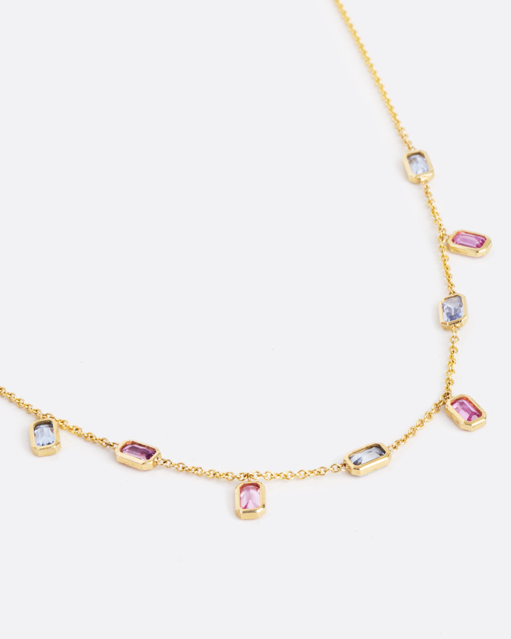 gold chain with 9 emerald cut sapphires set horizontally and vertically along the chain